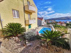 a building with a swimming pool next to a house at Apartments Villa Jelena in Seget Vranjica