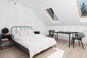 a white bedroom with a bed and a desk at Chillax Apartments in Zator