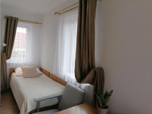 a bedroom with a bed and a chair and a window at Pokoje Goscinne Kamako in Dźwirzyno