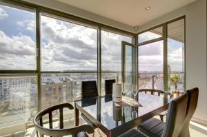 a dining room with a table and chairs and large windows at Helios Luxury apartment in Vilnius skyscraper in Vilnius