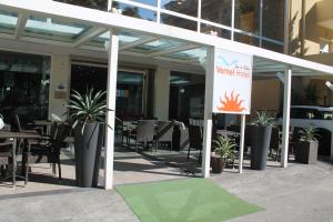 een patio met tafels en stoelen en een bord bij Hotel Vernel in Rimini