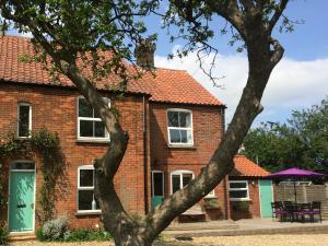 une maison en briques avec un toit orange dans l'établissement Dairy Barns Holiday Cottages, à Norwich