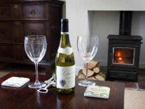ノリッジにあるDairy Barns Holiday Cottagesのワイン1本とワイングラス2杯(テーブル上)
