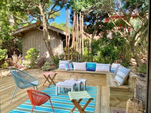 un patio con sofá y sillas en una terraza en La Maison Bleue, en Cap-Ferret