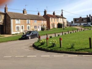 a car parked on the side of a road with houses at Chalk and Cheese in Shouldham Thorpe