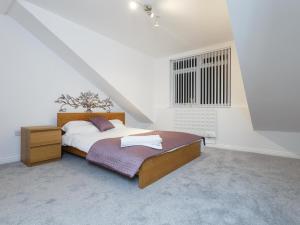 a white bedroom with a bed and a window at Ruth Apartments in Leeds