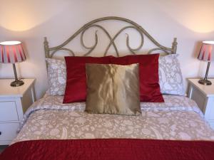 a bedroom with a bed with red pillows and two lamps at Shrubbery Guest House in Worcester