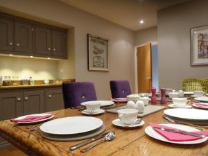 a dining room table with white plates and purple chairs at The Barn At Woodview in Hildenborough