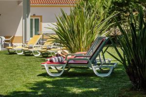 a row of lounge chairs sitting on the grass at Quinta do Peru I in Quinta do Conde