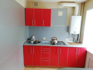 a kitchen with red cabinets and a sink at Apartment On Oktyabrskaya 4 in Ukhta