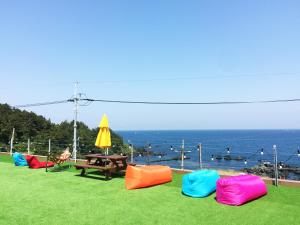 un grupo de sillas sentadas en la hierba cerca del océano en Yesjun Guest house en Jeju