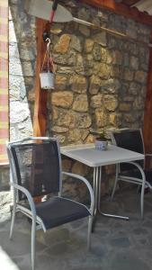 una mesa blanca y 2 sillas junto a una pared de piedra en Apartment CLIA en Ohrid