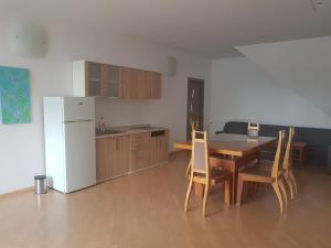 a kitchen with a table and chairs and a white refrigerator at Lara Guest House in Sfântu-Gheorghe