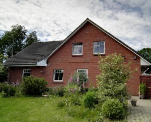 ein rotes Backsteinhaus mit Fenstern und einem Hof in der Unterkunft Ferienwohnung Seegaard in Husby