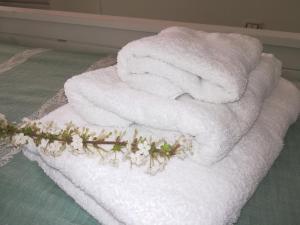 a pile of towels sitting on a bed with flowers at Antico Casale Il Sambuco in Manduria