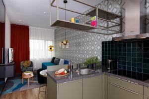 a kitchen with a sink and a living room at Citadines Sloterdijk Station Amsterdam in Amsterdam