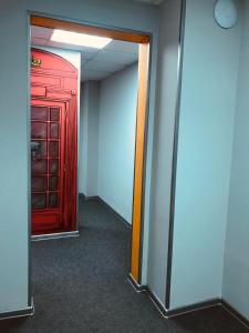 um corredor vazio com uma porta vermelha e uma sala com um hallwayngth em Hostel Ovsyanka em Yuzhno-Sakhalinsk