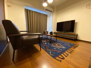 uma sala de estar com uma cadeira e uma televisão de ecrã plano em Residential Hotel Bevel Tokyo em Tóquio