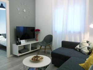 uma sala de estar com um sofá, uma televisão e uma mesa em DL Patio Málaga em Málaga