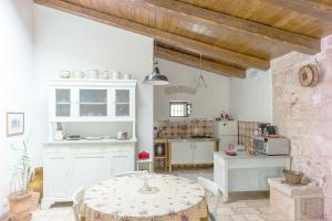 una cucina con tavolo e una cucina con armadietti bianchi di Depéndance a Polignano a Mare