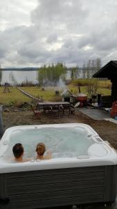 2 personas en una bañera de hidromasaje con vistas al lago en Villa Rauha, en Kittilä