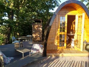 Cette petite cabane en bois dispose d'une terrasse avec une table et des chaises. dans l'établissement Weids Zicht BB Weidszicht, à Doezum