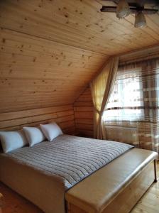 Cama en habitación de madera con ventana en Катерина, en Rozhanka Nizhnyaya