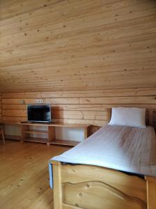 1 dormitorio con 1 cama en una pared de madera en Катерина, en Rozhanka Nizhnyaya