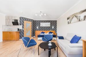 a living room with a white couch and blue chairs at Jantar Apartamenty Sunny Olymp I in Kołobrzeg