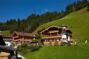 ein großes Gebäude auf einem Hügel mit grünem Hang in der Unterkunft Landhaus Staudacher in Gerlos