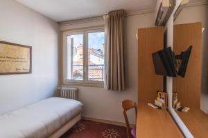 a room with a bed and a tv and a window at Hotel Ours Blanc - Place Victor Hugo in Toulouse