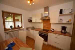 uma cozinha com armários brancos e uma mesa de madeira em Ferienhaus Rosa 2 & 5 em Füssen