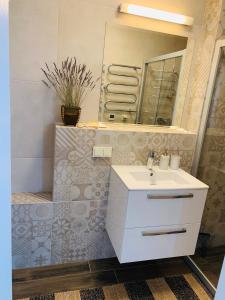 bagno con lavandino bianco e specchio di Lagoon Attic Apartment Pervalka a Pervalka