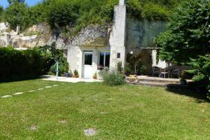 una piccola casa in pietra con un cortile verde di Caves du coteau 1 a Lunay