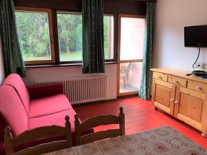 a living room with a pink chair and windows at Residence Trunka Lunka in Cavalese