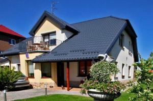 une maison avec un toit noir et une cour dans l'établissement Kwatery prywatne pokoje i apartament JOANNA w Grzybowie, à Grzybowo