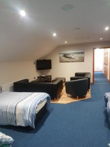 a hotel room with a bed and a tv and chairs at Reubens Loft in Bushmills