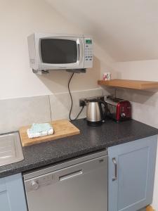 a small kitchen with a microwave and a counter top at Reubens Loft in Bushmills