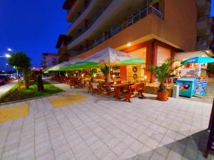 ein Restaurant mit Tischen und Sonnenschirmen vor einem Gebäude in der Unterkunft Hotel Ancora Beach in Primorsko