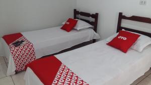 two beds in a room with red and white pillows at OYO Pousada Paraná in Cuiabá