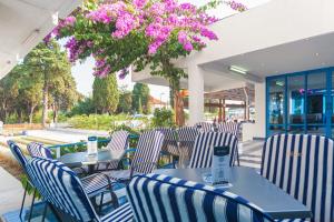 eine Terrasse mit Stühlen und Tischen mit lila Blumen in der Unterkunft Hotel Bolero in Biograd na Moru