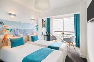 a hotel room with two beds and a table at Best Western Hôtel Royan Océan in Royan