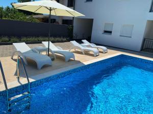 a swimming pool with lounge chairs and an umbrella next to it at Villa Lord in Pomer