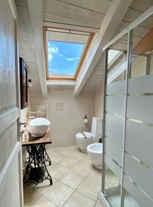 een badkamer met 2 wastafels en een dakraam bij La Chiocciola in Momo