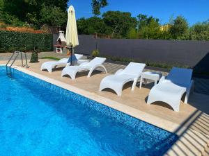een groep stoelen en een zwembad met een parasol bij Villa Lord in Pomer
