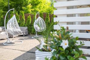 2 witte stoelen en bloemen op een patio bij Hotel Mistral in Marki