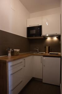 eine Küche mit weißen Schränken und einer Mikrowelle in der Unterkunft Apartmán Dagmar in Bešeňová