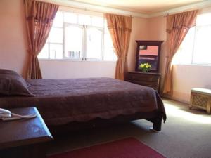 um quarto com uma cama, um espelho e janelas em Apart Hotel Turquesa em Potosí