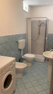 a bathroom with a toilet and a shower with a washing machine at Home Fiesta in Giardini Naxos
