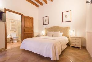 a bedroom with a large white bed and a bathroom at Petit Hotel Alaro in Alaró